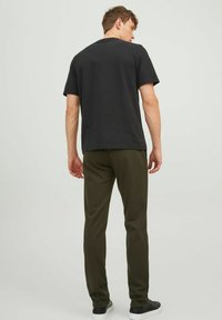 Camiseta negra de manga corta y pantalones verdes oliva, diseño sencillo, ajustado, material de algodón, textura suave, combinados con zapatillas negras.
