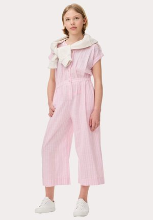 Une combinaison courte à manches courtes de couleur rose clair avec des rayures verticales blanches, un devant à boutons, une taille élastique et des jambes larges et cropped. Un pull blanc drapé autour du cou.
