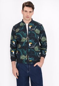Heren bomberjack met een tropische print van toekans en palmbladeren, in tinten groen en zwart, met ribgebreide manchetten en kraag.