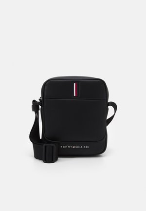 Sac bandoulière rectangulaire noir avec sangle réglable, poche avant et logo Tommy Hilfiger avec des bandes rouges, blanches et bleues.