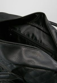 Black leather bag with a quilted exterior, featuring a zippered main compartment and a separate zippered pocket inside.