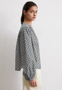 Langärmlige Bluse aus leichtem Stoff mit einem mehrfarbigen Sternmuster, Rundhalsausschnitt und gerafften Ärmeln. Bietet einen lockeren Schnitt.