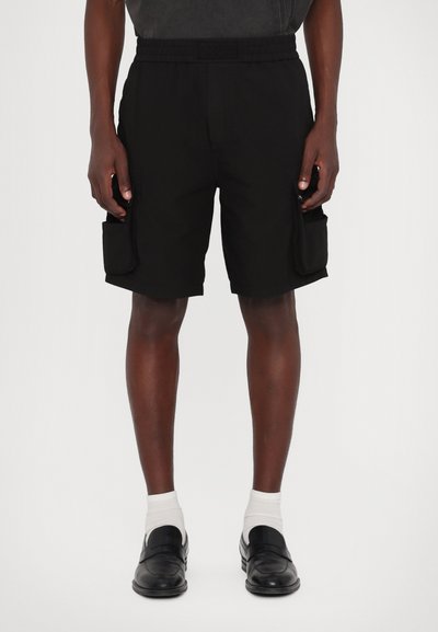 Shorts cargo din material negru au o talie elastică, două buzunare laterale mari și o croială lejeră. Textura pare ușoară și durabilă.