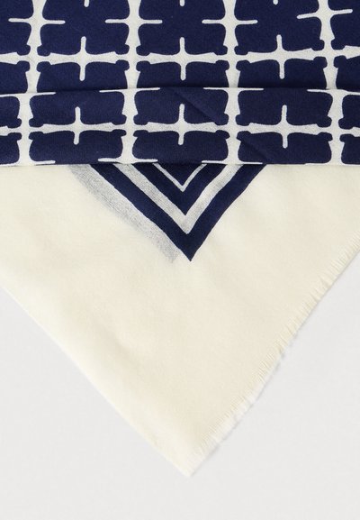 Μαντήλι σε σκούρο μπλε και λευκό με γεωμετρικά σχήματα, με κρέμ περιθώριο και διαγώνια άκρη. Το ύφασμα φαίνεται μαλακό με υφή κρόσσια.