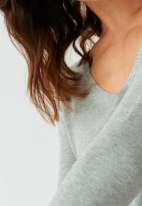 Grau Baumwollpullover mit weicher Textur, breitem Ausschnitt und lockerer Passform, teilweise sichtbarem Schulterbereich und langen Ärmeln.