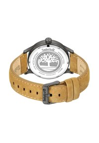 Timberland pulkstenis ir aprīkots ar apaļu nerūdīgo tēraudu korpusu, gaiši brūnu zamšādas jostu, ar logotipu iegravētu sprādzi un sudrabotu aizmuguri ar koku simbolu.