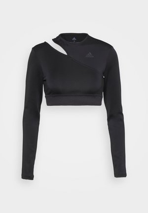 Zwarte crop top met lange mouwen van rekbaar materiaal, met een asymmetrisch ontwerp met een uitsparing bij de hals en een logo op de borst.