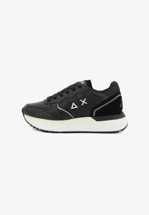 Baskets noires avec semelle blanche, présentant des symboles de triangle et de croix sur le côté, lacets noirs et détails de couture blanche sur le talon.