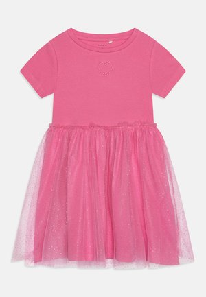 Różowa sukienka z krótkim rękawem, wyróżniająca się haftem w kształcie serca. Spódnica ma warstwowy tiulowy nadkład z błyszczącymi akcentami.
