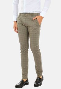 Pantaloni da uomo su misura in verde oliva chiaro con motivo a quadri, dotati di chiusura con bottone e tasche frontali. Tessuto morbido.