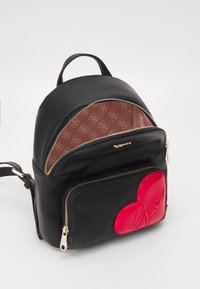 Czarny plecak z faux skóry z złotymi akcentami. Posiada różowy, sercowy element dekoracyjny oraz zapinaną na zamek kieszeń z przodu. Wnętrze wyłożone tkaniną.