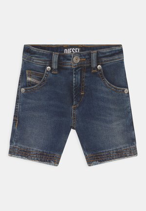 Bermudas de ganga em azul escuro com um acabamento desgastado, cinco bolsos, botão de metal e rebites, e costura em contraste ao longo das costuras.