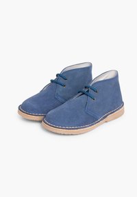 Botine din piele întoarsă albastră cu tălpi din cauciuc bej, având un design simplu de șireturi și cusături decorative în jurul marginilor.