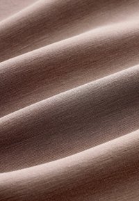 Texturiertes, leichtes Gewebe in einem sanften Mauve-Ton, das feine Rillen und glatte Oberflächen aufweist und sanfte Falten und Drapierungen kreiert.