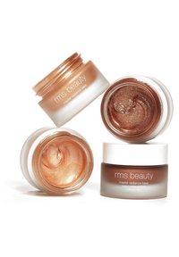 Quattro barattoli di RMS Beauty contenenti Master Radiance Base: due con bronzo scintillante, uno rame e uno bronzo scuro; texture cremose e lisce.