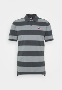 Šedé a tmavě šedé široce pruhované polokošile s krátkým rukávem, černým límečkem a logem Nike na levé hrudi.