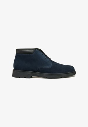 Marineblauwe suede enkellaarsjes met zwarte leren accenten, uitgerust met een ronde neus, vetersluiting en een gemarmerde rubberen zool voor grip.