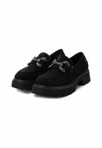 Mocasines de plataforma de ante negro con suela gruesa y un acento decorativo de cadena plateada a lo largo de la parte superior. Textura suave y diseño estructurado.