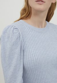 Világoskék kötött pulóver bordázott textúrával, kerek nyakkivágással és puffos ujjakkal, amely puha és könnyű anyagból készült.