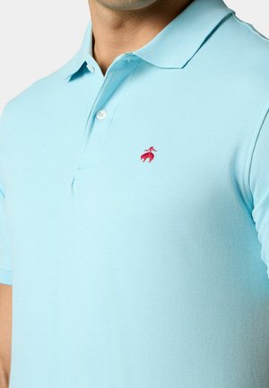 Lichtblauwe poloshirt van gestructureerde stof, met een rood geborduurd logo op de linkerborst en een klassieke kraag met twee knopen.