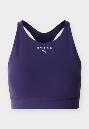 Brassière de sport bleu marine avec design dos nageur, comportant le logo blanc "HYROX" et le logo Puma au centre avant.