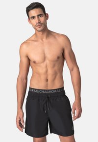 Black swim shorts with an elastic waistband featuring a gray logo band and drawstring. Made from lightweight, quick-drying material.