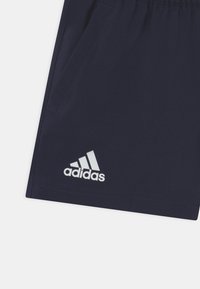 Mörkblå atletiska shorts i mjukt tyg med resår i midjan, utrustade med framfickor och en vit Adidas-logotyp nära fållen.