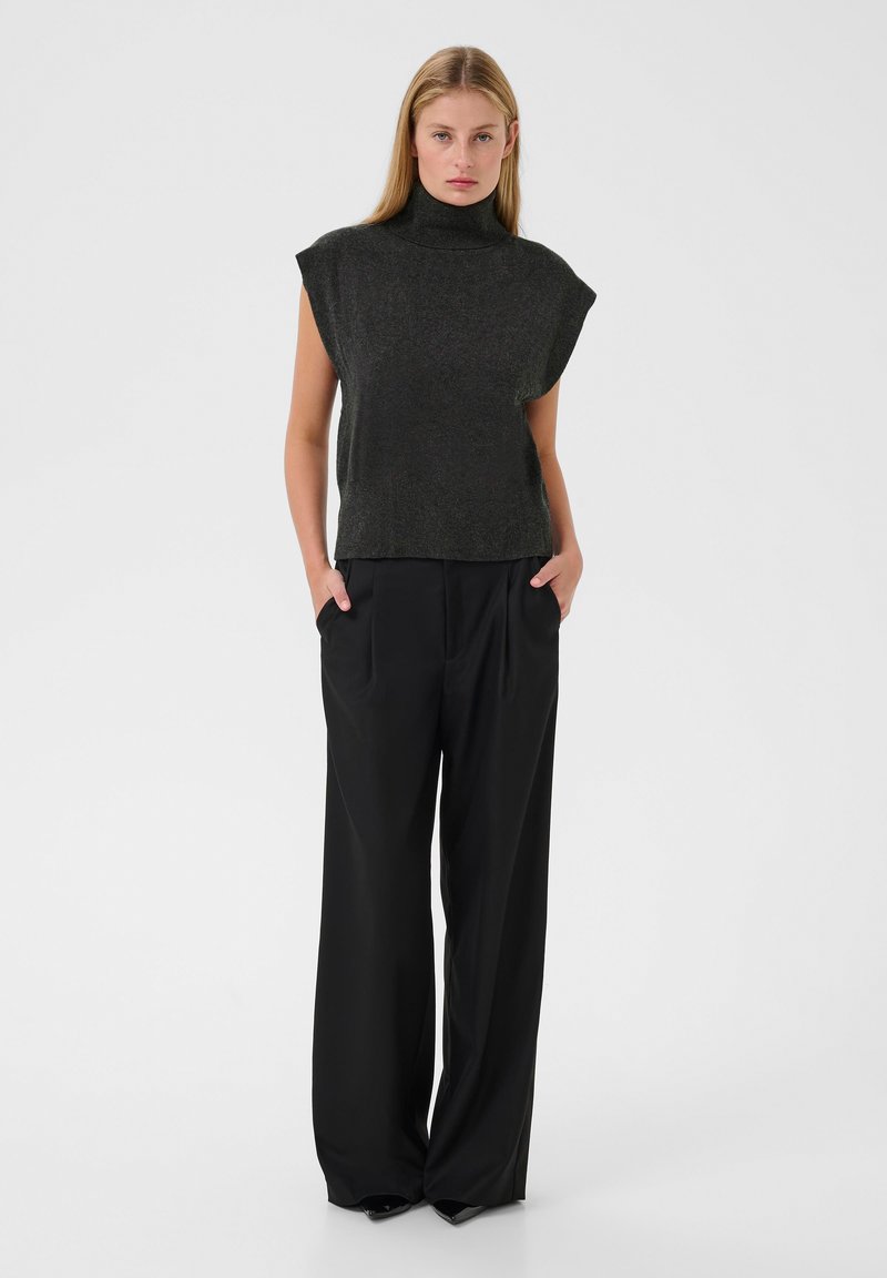 Dunkelgraues ärmelloses Rollkragenoberteil mit lockerem Schnitt, kombiniert mit hochtaillierten schwarzen weiten Hosen. Glatte Textur und minimalistisches Design.