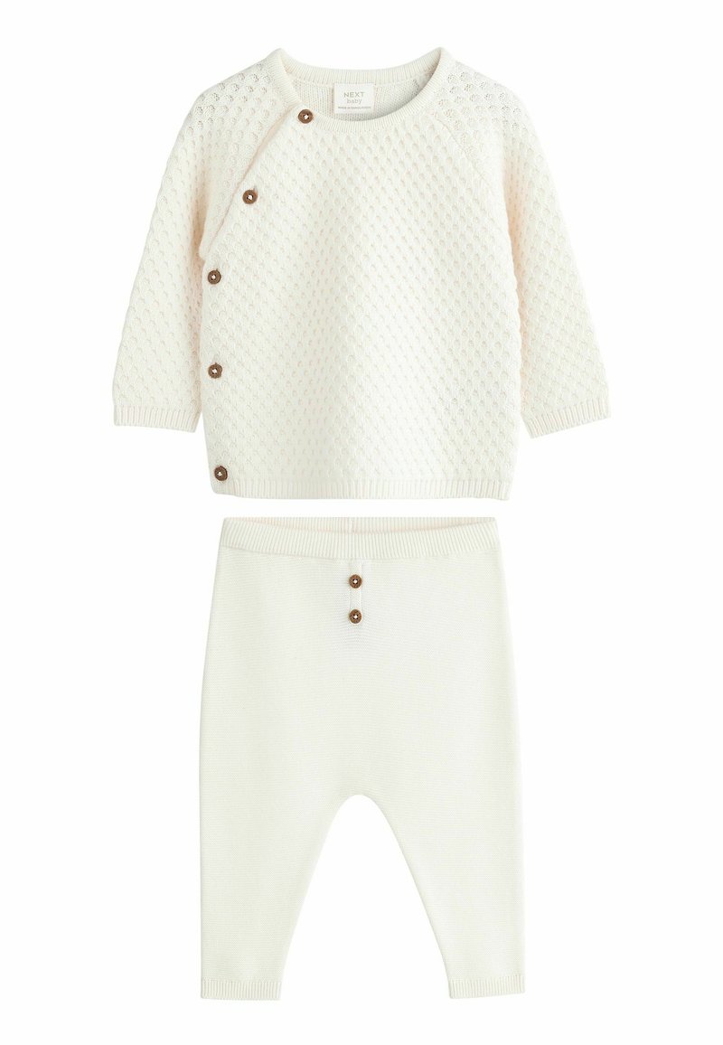 Pull bébé en tricot crème avec motif texturé et pantalon assorti, tous deux avec des boutons marron en accents.