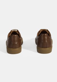 Braune Lederschuhe mit strukturierten Oberflächen und einer niedrigen Gummisohle. Verfügt über eine Schlaufe für einen einfachen Griff an der Ferse.