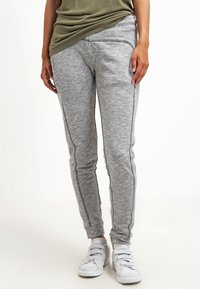 Grå sweatpants med en texturerad tygkvalitet, slim fit och kontrasterande sömmar. Matchas med vita sneakers och en grön topp.