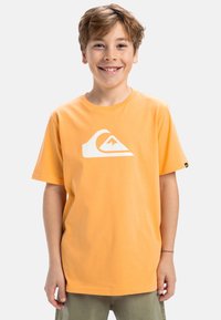 Camiseta de algodón naranja con un gran logo de ola blanca en la parte frontal. Mangas cortas, cuello redondo y un ajuste relajado.