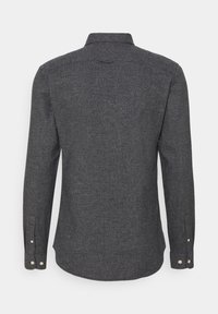Chemise à manches longues gris foncé en tissu texturé. Présente un col et des poignets boutonnés, avec un ourlet légèrement arrondi.