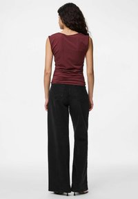 Bordový bezramínkový top se přiléhavým střihem; spárován s vysokým pasem a širokými džínami černé barvy; hladká bavlněná textura, jednoduché švy.