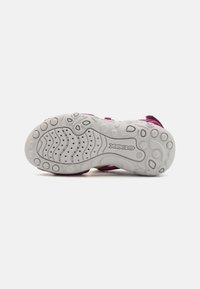 Zapatillas para niños en tonos rosa y gris con una suela de goma texturizada. Presentan un diseño flexible y una correa ajustable para un ajuste seguro.