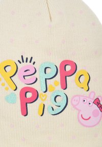 Beanie crema con una texture a coste, caratterizzato da un vivace testo "Peppa Pig" e un grafico del volto di Peppa con un fiocco. Motivo a pois rosa.