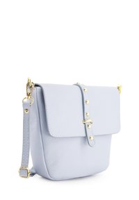Lichtblauwe leren schoudertas met een klep sluiting, voorzien van gouden hardware en decoratieve studs langs de strap. Gladde textuur.