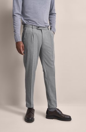 Gray pleated trousers made of textured fabric, featuring side pockets and a button closure, paired with dark leather shoes.