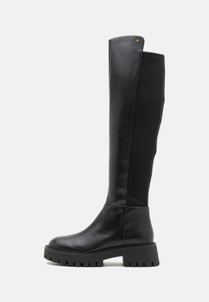 Stivali in pelle nera al ginocchio con finitura liscia, suola in gomma spessa, punta arrotondata e un pannello di tessuto a contrasto sul retro.