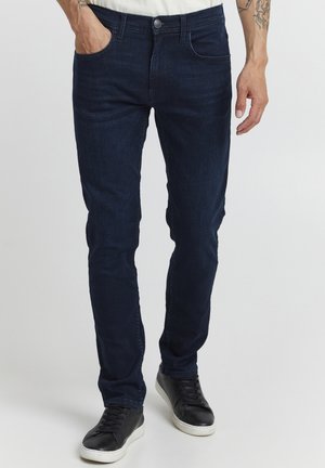 Donkerblauwe denim jeans met een slim fit, vijf-pocket ontwerp en een subtiele textuur. Knopsluiting en riemlussen zichtbaar op de taille.