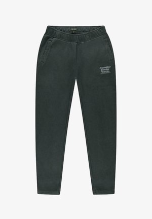 Donkergroene trainingsbroek van zacht materiaal, met zijzakken en een elastische tailleband, met een gedrukt tekstdetail op de linker dij.