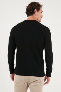 Schwarzes Langarmshirt mit gerippter Textur, runder Ausschnitt und enganliegenden Ärmeln. Verfügt über einen geraden Saum und ein minimalistisches Design.