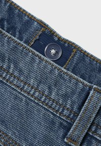 Denimstof in een diepe blauwe kleur, met een doorzichtige plastic knop en contrasterende gele stiksels langs de naden en zakken.