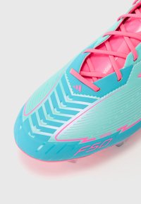 Bright blue soccer cleat with pink accents, featuring a textured surface, diagonal stripes, and prominent branding on the side.