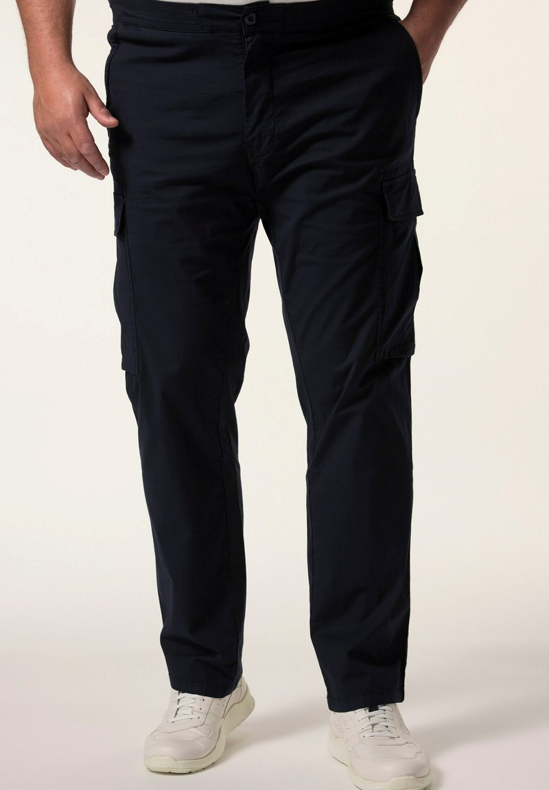 Námořnické modré cargo kalhoty vyrobené z lehkého materiálu, s několika bočními kapsami a rovnými nohavicemi. Nosené s bílými teniskami.