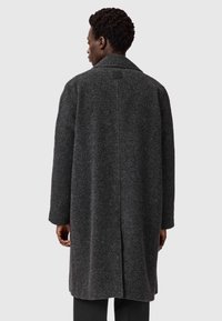 Grå uld frakke med afslappet pasform, lange ærmer, reverskrave og rygventilation. Har et mærke ved halsen og en struktureret overflade.