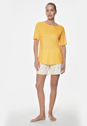 Yellow short-sleeve top paired with white shorts featuring a floral pattern in yellow and purple. Soft fabric with relaxed fit.