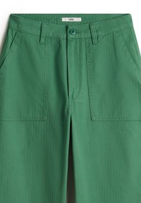 Groene katoenen broek met een rits- en knoopsluiting, twee voorzakken en een gestructureerd oppervlak. Label zichtbaar bij de tailleband.