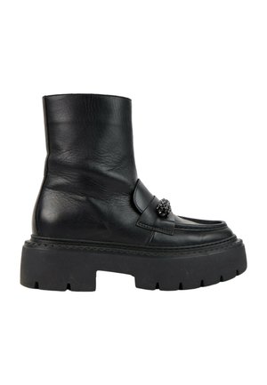 Bottine en cuir noir avec semelle à crampons épaisse et ornement noir décoratif sur la bride avant, vue de côté sur fond blanc.
