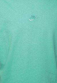 Mintgrön bomullströja med en broderad Nike-logga i en något mörkare nyans. Mjuk textur med en enkel design.